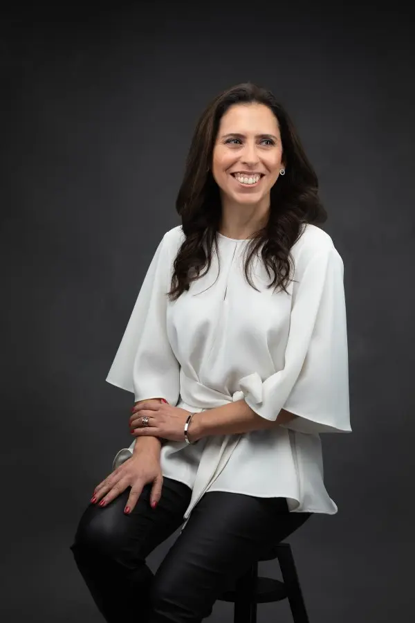 Coach Lourdes Monteiro sentada numa cadeira sorrindo para a câmara